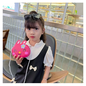 Close-up of pink bunny mini crossbody bag with woven strap on a child model