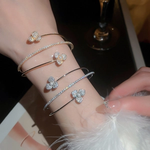 Detailed close-up of layered flower bracelets with zircons and pearls on a wrist