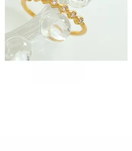 Macro shot of gold-plated wavy ring featuring fine micro-set sparkling crystals