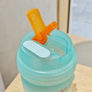 Frosted green dual-drink water bottle with bright orange lid and open button detail