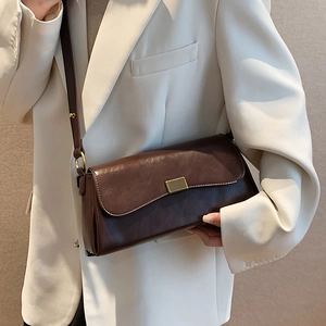 Dunkelbraune Leder-Umhängetasche mit verstellbarem Riemen und goldener Schnalle an Model