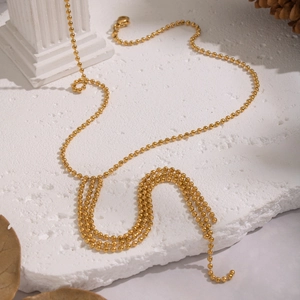 Elegant gold 304 stainless steel Y-shaped beaded tassel necklace on a white stone base