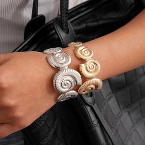 Close-up of spiral nautilus shell open bracelets in gold and silver finish with detailed lines