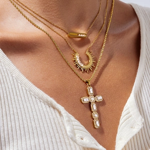 Layered gold necklace featuring sparkling cross and celestial pendants on model