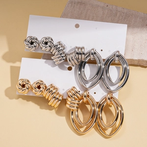 Close-up of gold and silver metallic earring sets featuring twisted knots and oval hoops