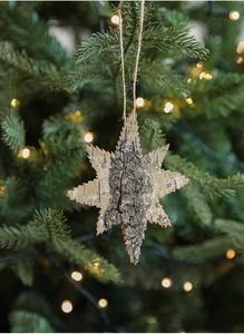 Close-up of star-shaped natural bark ornament hanging on a festive Christmas tree branch