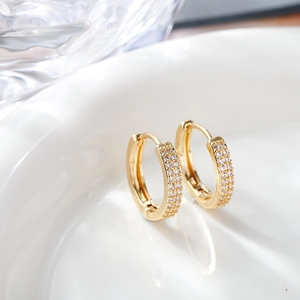 Macro shot of gold zircon hoop earrings with micro-pave crystals on white ceramic