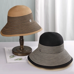 Detailed texture of striped woven straw sun hat with elegant wide brim and metal logo