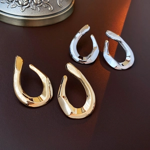 Macro shot of twisted U-shape metal earrings in polished gold and silver finishes