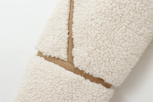 Détail de polaire sherpa blanche cousue avec du faux daim marron sur la veste