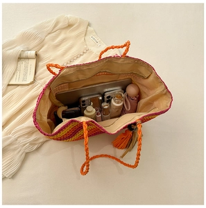 Detail showing high capacity of striped straw tote bag with inner lining and orange handles