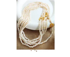 Macro detail of multi-strand freshwater pearl necklace with golden floral petal buckles