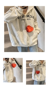 Detail shot of a red heart-shaped mini chain bag paired with a grey zip-up hoodie