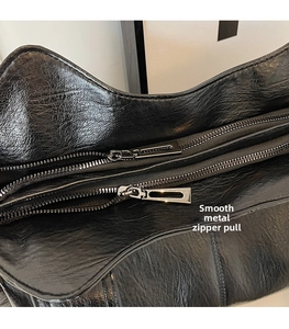 Close-up of smooth silver metal zippers on black vintage leather tote bag detail