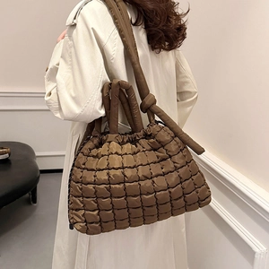 Brown quilted puffer tote bag with top handles and shoulder strap shown on model