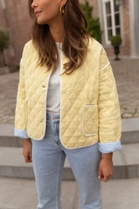 Detail of yellow quilted diamond jacket with contrast white piping and striped sleeve lining
