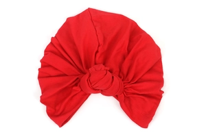 Detail of red elastic turban hat with large handmade knot on soft knitted fabric