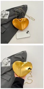Close-up of heart-shaped gold acrylic evening clutch with metallic chain and glossy finish