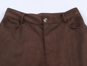 Macro view of high-waist suede trousers featuring a single amber button and side pockets