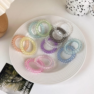 Macro shot of colorful spiral hair ties on a white ceramic plate with a fresh aesthetic