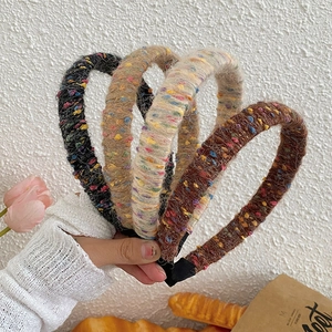 Detail showing four tweed headbands in black, beige, white and brown with rich textures