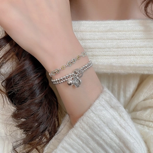 Detail of layered enamel flower bracelets with silver beads and a floral charm pendant