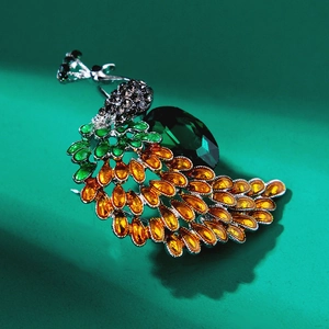Detailed close-up of a vintage peacock brooch with green rhinestones and silver alloy base