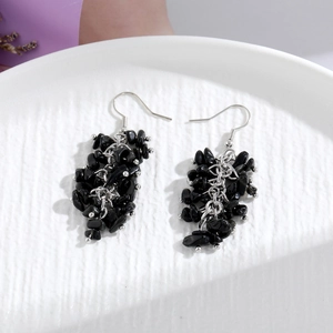 Close-up of long tassel earrings with black natural stone chips and silver metal beads