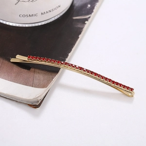 Macro detail of golden metal hair clip with row of sparkling red round rhinestones