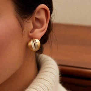 Close-up of gold C-shaped crossover earrings with pavé zircon on model's ear