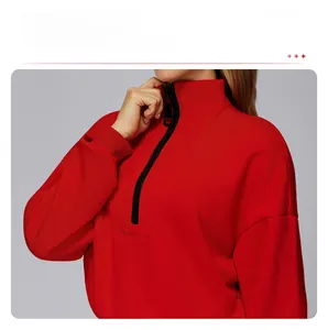 Detail of red stand-collar sweatshirt featuring drop shoulder cut and black half-zipper