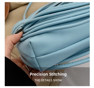 Detail showing the precision stitching and pleats on a light blue woven shoulder bag