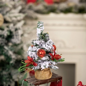Miniature Christmas tree with faux snow and red ornaments on a vintage red sled base