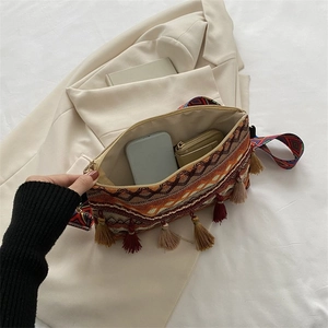 Detail view of ethnic woven crossbody bag with colorful tassels and geometric strap