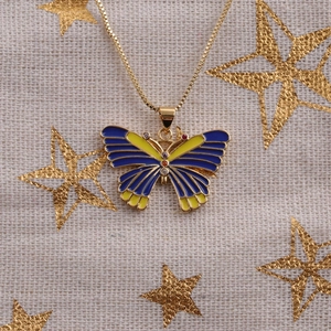 Detail view of a gold-plated butterfly pendant with blue enamel and crystal accents