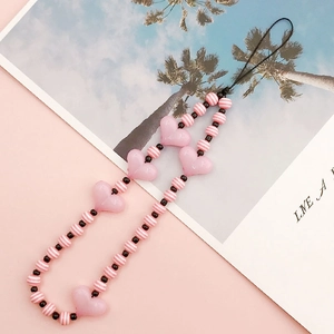 Detail of handmade beaded phone strap with pink heart acrylic beads and striped resin charms