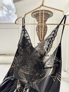 Détail d'une chemise de nuit en satin noir avec dentelle papillon et motifs dorés élégants