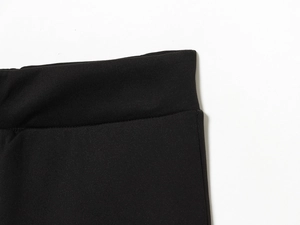 Detailed macro view of the high-elastic waist and fine stitching on black knit trousers