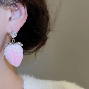 Macro shot of pink flocked strawberry earring with heart-shaped zircon stud on a model