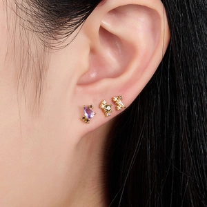 Macro view of S925 silver stud earrings set with colorful zircons on a model's ear