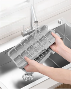 Detailed view of washing a flexible grey silicone sink mat with a multi-grid drainage design