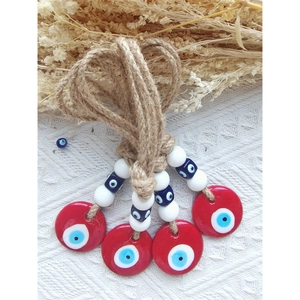 Detail of four handmade jute rope evil eye wall hangings with red and blue glass beads