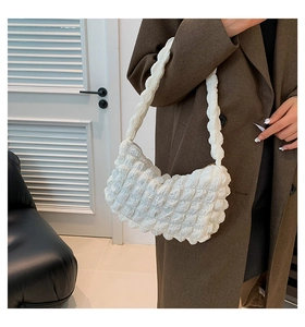 Détail du sac blanc à texture bulle avec tissu matelassé porté à l'épaule sur modèle