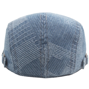 Detail view of denim flat cap showing patchwork stitching and adjustable side buckles