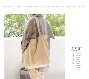 Detail of a beige canvas tote bag with long straps in a minimalist outdoor setting