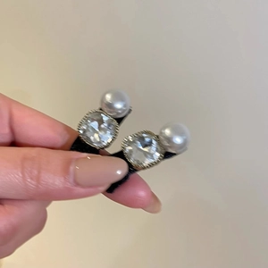 Gros plan de boucles d'oreilles avec strass carrés et perles blanches sur monture dorée
