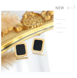 Detail view of square gold earrings with black enamel inlay and Roman numeral engraving