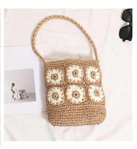 Detailed close-up of handmade straw shoulder bag with white daisy crochet pattern