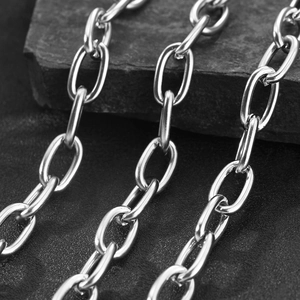 Macro shot of polished silver stainless steel oval link chain on a black textured stone