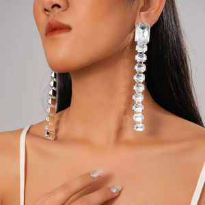 Close-up of elegant silver tassel earrings with rectangular rhinestones on a model